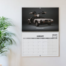 Load image into Gallery viewer, Wall calendar with a DeLorean DMC-12 car design on a white wall.